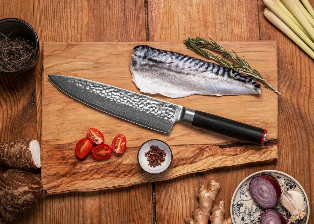 kotai pakka damascus koksmes gyuto 20 cm pakkahout op houten snijplank met vis en tomaat